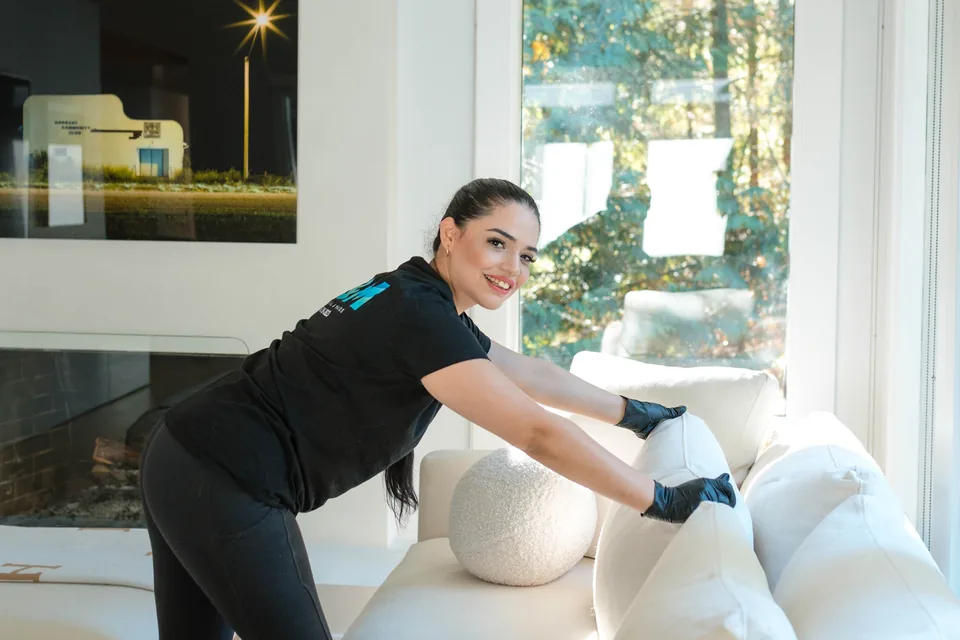 C&M cleaner cleaning a sofa in a bright living room