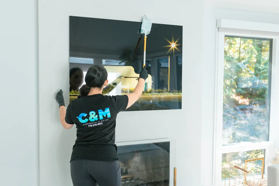 C&M cleaner dusting above a fireplace in a living room