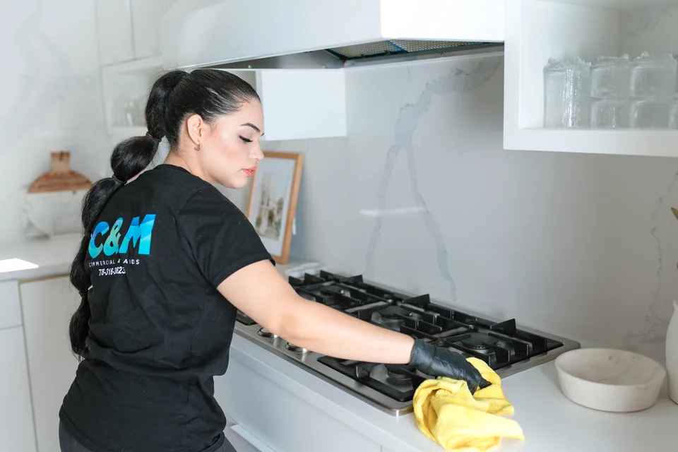 C&M cleaner wiping a gas stove in a Vancouver kitchen